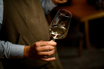 the bartender holds a glass of wine in his hands