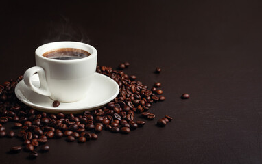 Coffee in white cup with coffee beans on dark surface in selective focus