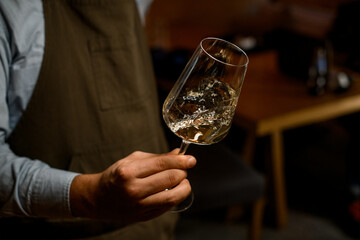 the bartender holds a glass of wine in his hands