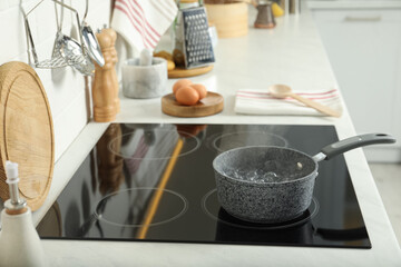 Saucepan with boiling water on electric stove in kitchen. Cooking utensil