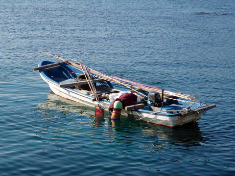 Japanese local fisherman, hooking shellfish like awabi, uni, seaweed, from the bottom of the sea.　箱眼鏡で貝や海藻を獲る漁師船の風景写真