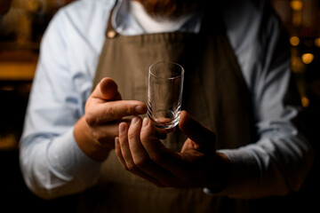 view of hands of male bartender with empty transparent glass