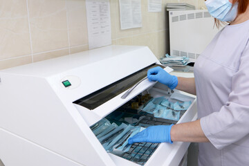 Sterilization of medical instruments in an autoclave. Dental office. A woman sterilizes medical instruments in an autoclave.