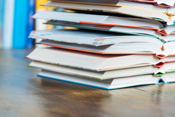 Close-up stack opened book on wooden desk with blurred soft library background