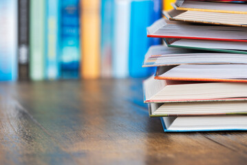 Stack opened book on wooden desk with blurred soft library background