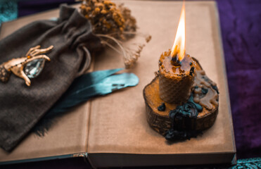 Illustration for esoteric contents, scene with a candle and book of spells , esoteric concept, fortune telling, other magic stuff on a table	
