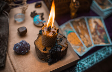 Illustration for esoteric contents, scene with a candle and book of spells , esoteric concept, fortune telling, other magic stuff on a table	
