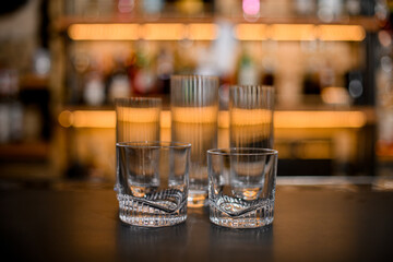 Set of empty clean glasses on dark bar counter.