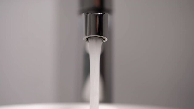 Opens the mixer valve. A jet of water runs from a water pipe.