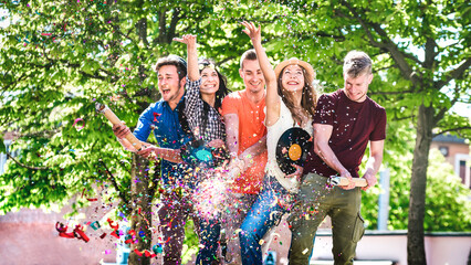 Happy amused friends having fun out side cheering with confetti - Young people enjoying spring...