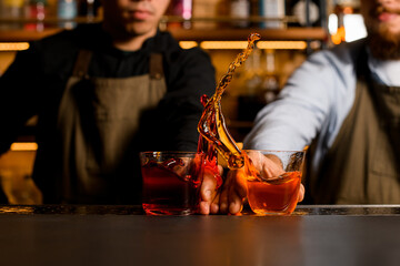 Two bartenders spectacularly making splash of two alcohol cocktails