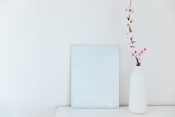 Almond blossom branches in a vase with picture frame mockup. White background, copy space.