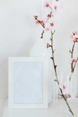 Almond blossom branches in a vase with picture frame mockup. White background, copy space.