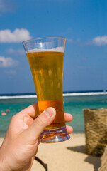 Hand with a glass of beer on the background of the sea