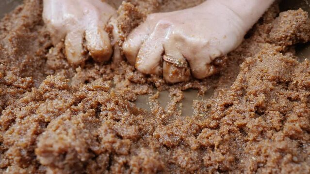 A Moroccan woman is kneading Argan paste, pulp. 4k. A step to extract oil from the popular Argan nuts. Traditional, handmade Argan oil, is rich in fatty acids and is used in cooking and cosmetics.