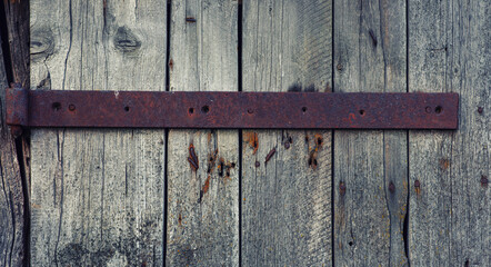 Old weathered wooden door with steel hinges. Distressed panels. Old wall texture background. Detail of an old wooden door with rusty door latch.