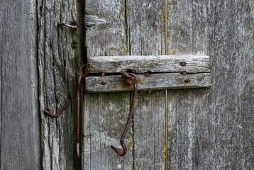 Old weathered wooden door with steel hinges. Distressed panels. Old wall texture background. Detail of an old wooden door with rusty door latch.