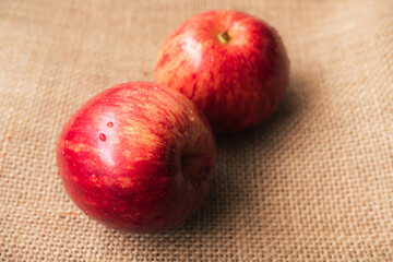 red apple, 2 sweet red apples placed on a brown sackcloth surface, ready to eat. Ripe red apples have a wet skin that looks and feels refreshed.