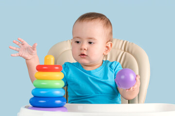 A beautiful toddler of 12-17 months is playing an educational game by assembling a pyramid of...