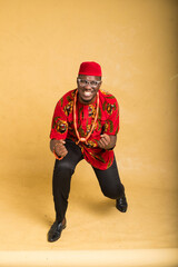 Igbo Traditionally Dressed Business Man in Glasses Happy with One Kneel Down