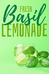 Glass of tasty basil lemonade on green background