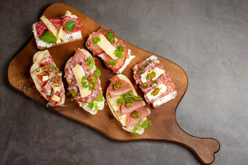Appetizers table with antipasti snacks. Brushetta or authentic traditional Spanish tapas set, cheese variety board and sour cream, placed on wooden serving board