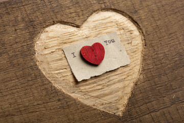 I love you - tiny typed text note close up. Valentines Day greetings concept. Carved heart shape on...