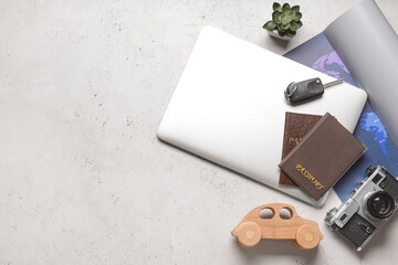 Fototapeta premium Laptop with toy car, photo camera, passports and map on light background