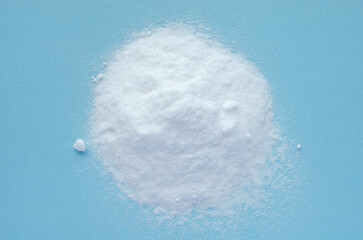 Pile of baking soda on a blue background, top view. Baking soda, sodium bicarbonate, on a blue background, top view. Baking soda powder, on a blue background, NaHCO3, top view.