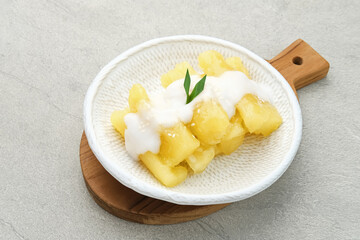 Singkong thailand, sweet cassava, made of boiled cassava, sugar and coconut milk. Served in plate with pandan leaf, selective focus and blurred background.
