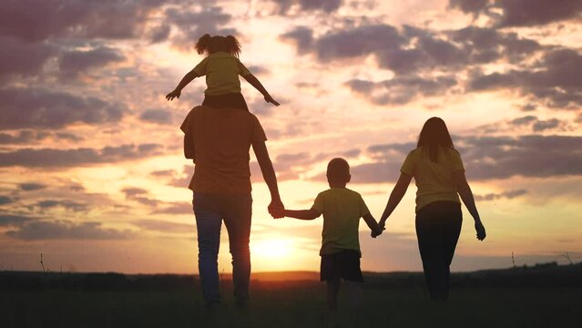 happy family walking together in the park silhouette. friendly family kid freedom concept. happy family walking holding hands in the park on the grass at sunset. friendly family together lifestyle