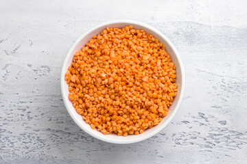 Raw soaked lentils in white bowl on light gray background, top view. Healthy Food Concept