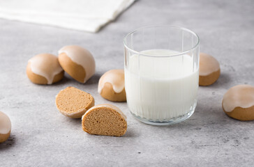 Wooden board with homemade steamed honey gingerbread with lemon icing and glass of milk  on gray background