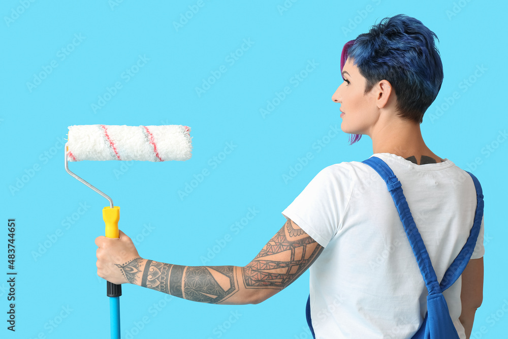 Sticker Female painter with bright hair and paint roller on blue background