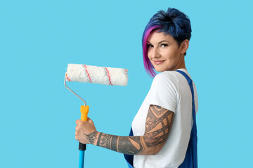 Female painter with bright hair and paint roller on blue background