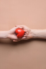 Female and male hands with red heart on color background. Donation concept