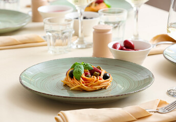 Plate of tasty Pasta Puttanesca on table in restaurant