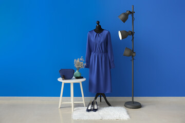 Interior of room with mannequin, table and floor lamp near color wall