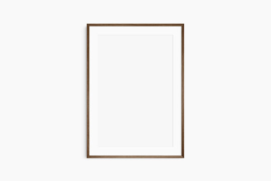 Frame mockup 5x7, 50x70, A4, A3, A2, A1. Single dark brown walnut wood frame mockup. Clean, modern, minimalist, bright. Portrait. Vertical. Passepartout/mat opening in 2:3 aspect ratio.