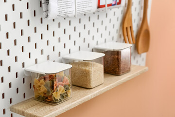 Jars with pasta and groats on pegboard, closeup
