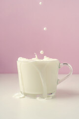 Milk is poured into a transparent cup on a purple background.