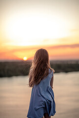 rear view of a girl standing and looking at the sunset