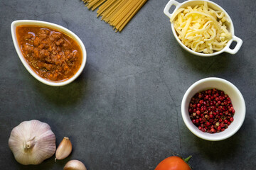 Italian food ingredients for spaghetti bolognese. Raw spaghetti pasta with various ingredient on gray background. Top view and copy space for your text.