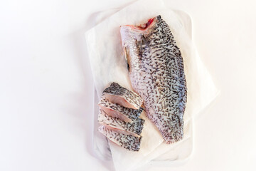 Fresh sea bass fish fillets on marble cutting board; selective focus and copy space.