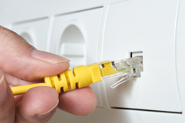 hand plugging rj45 ethernet cable into a network socket