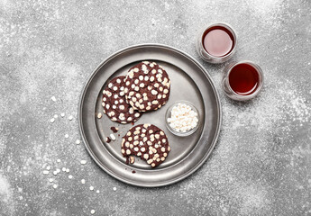 Plate of tasty cookies with white chocolate chips on grey background