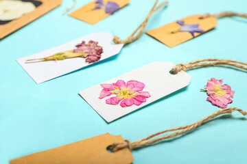 Tags with dried pressed flowers on turquoise background