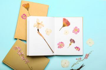 Books with dried pressed flowers on turquoise background
