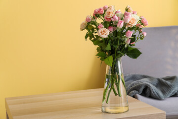 Vase with bouquet of beautiful roses on table in room