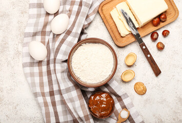 Bowl with flour and ingredients for preparing walnut shaped cookies with boiled condensed milk on light background